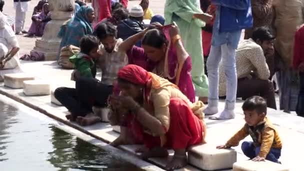 DELHI, INDIA - 11 maart 2019: een moslimvrouw in een rode sari wast haar gezicht in de jama masjid moskee — Stockvideo