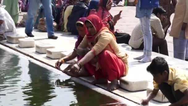 DELHI, INDIA - 11 maart 2019: een vrouw in een rode sari wast haar armen in de jama masjid moskee — Stockvideo