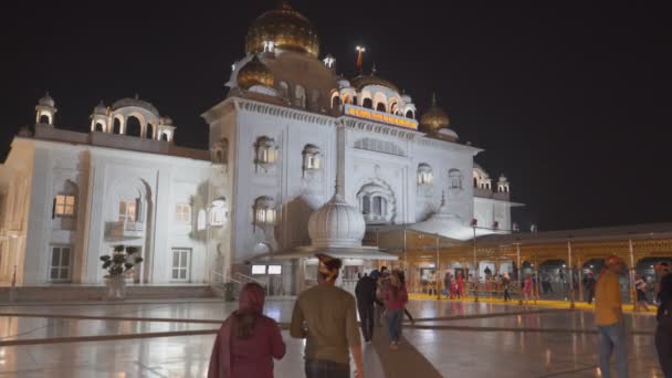 DELHI, INDIA - 13 Μαρτίου 2019: νυχτερινό πλάνο του μπροστινού μέρους του gurudwara bangla sahib με πιστούς στο Νέο Δελχί — Αρχείο Βίντεο