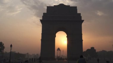 Gün doğumunda Hindistan kapısına doğru yürüyen bir vibratör ve kemer içinde güneş.