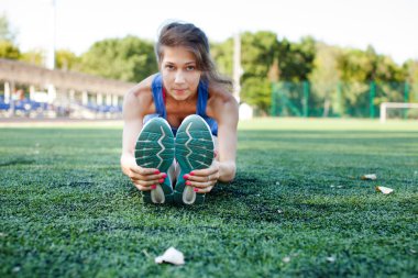 Parkın dışında spor salonunda esneme hareketleri yapan bir kadın. Parkta spor yaptıktan sonra esnek egzersiz yapan güzel formda bir bayan fitness mankeni. Sağlıklı yaşam tarzı kavramı