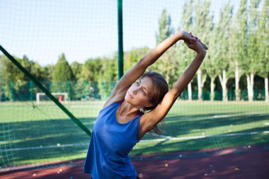 Parkın dışında spor salonunda esneme hareketleri yapan bir kadın. Parkta spor yaptıktan sonra esnek egzersiz yapan güzel formda bir bayan fitness mankeni. Sağlıklı yaşam tarzı kavramı
