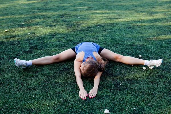 Vrouw stretching in fitness-oefening buiten door park. Mooi fit vrouwelijk fitness meisje model op park doet stretch training na de training. Gezond levensstijl concept — Stockfoto