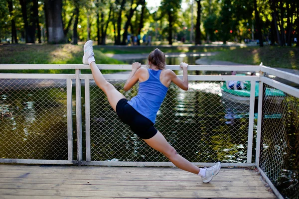 Kvinna stretching i fitness motion utanför genom park. Vacker passform kvinnlig fitness flicka modell på park gör stretch träning efter träning. Friska livsstil koncept — Stockfoto