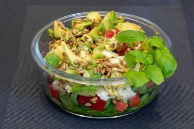 Avokado salatası ve roket ve ayçiçeği tohumlu domatesler.