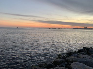 Denizin üzerinde gün batımı. Kumsaldaki kovan taşları