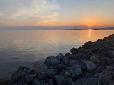 Denizin üzerinde gün batımı. Kumsaldaki kovan taşları