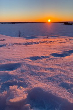 Sunset over the field covered with snow