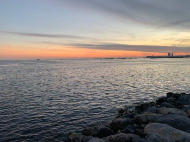 Denizin üzerinde gün batımı. Kumsaldaki kovan taşları