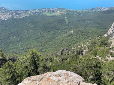 Dağ tepeleri ve kayalarla kaplı bir manzara. Aşağıdaki deniz