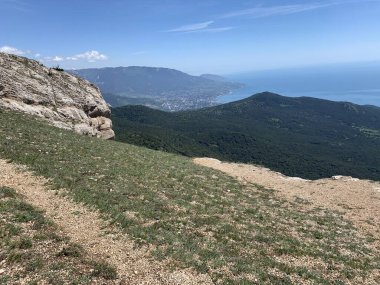 Dağ tepeleri ve kayalarla kaplı bir manzara. Aşağıdaki deniz