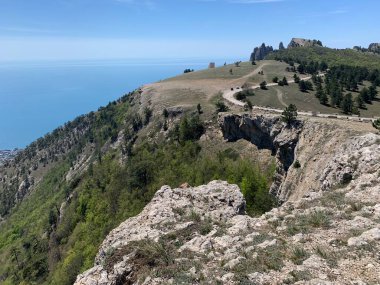 Dağ tepeleri ve kayalarla kaplı bir manzara. Aşağıdaki deniz