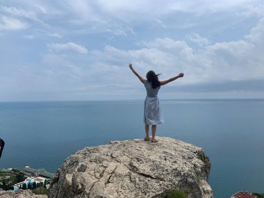 Uçurumun kenarında duran genç ve mutlu bir kadın. aşağıdaki deniz
