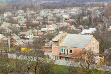 Soğuk mevsimde tuğlalı evler, yoğun çatılar, yapraksız ağaçlar ve kırsal manzaralı sakin bir köy manzarası..