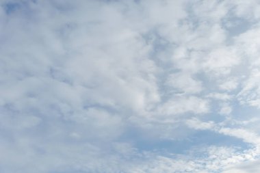 Yumuşak beyaz bulutlarla dolu parlak mavi gökyüzü hava, iklim ve açık hava temaları için ideal sakin bir doğal zemin oluşturuyor..