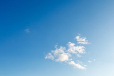 Açık mavi gökyüzü, yumuşak beyaz bulutlar yavaşça sürükleniyor, sakin bir doğal arka plan yaratıyor, hava ve yaz kavramları için ideal..