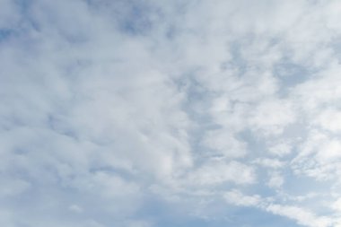 Yumuşak beyaz bulutlarla dolu parlak mavi gökyüzü hava, iklim ve açık hava temaları için ideal sakin bir doğal zemin oluşturuyor..