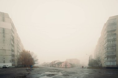 09.11. 2015, Romny, Ukrayna: Kalın sabah sisi, ıslak kaldırım ve küçük şehirde sakin atmosferde yerleşim yerlerinin bulunduğu kentsel sokak blokları kayboluyor.