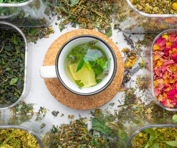 assortment of dry healing herbs and tea in cup with lemon and mint. Alternative medicine concept