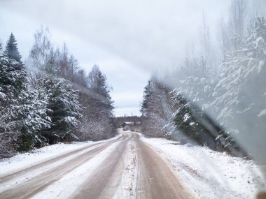Çam ağaçlarıyla çevrili karlı yol, bir kır yolunda kış karında sürmek, seçici odak ve hareket efekti