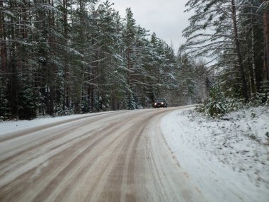 Çam ağaçlarıyla çevrili karlı yol, bir kır yolunda kış karında sürmek, seçici odak ve hareket efekti