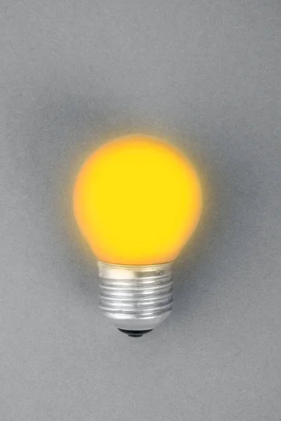 Illuminating Yellow lamp on trendy ultimate grey background. Creative idea concept. Minimalism. Top view. Flat lay. Lighting, electricity with light bulb, modern interior item with trendy colors of 2021