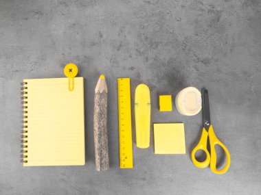 Moda renkleri üzerine aksesuar geçmişi olan bir ofis masası, gri arka planda okul sarı malzemeleri. Düz yerde, üst tarafta. Okul konseptine geri dönelim. Metin için boşluk kopyala