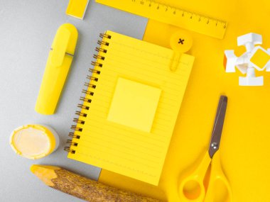 Sarı ve gri arkaplanlı okul ya da ofis aksesuarları. Okula dönüş kavramı. Düz konum: not defteri kalem, bileyici, makas, cetvel, trend aydınlatıcı sarı ve nihai gri arkaplan üzerine.