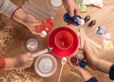 Çocuk elleri evde sümüklü oyuncak yapıyor. Sümük yapıyorum. Malzemeler ve bileşenler karıştırılır, çocukların yaratıcılığı kapalı alanda tatil yapar