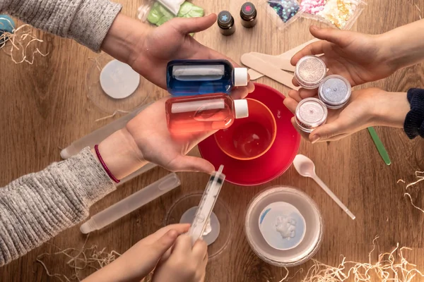 Çocuk elleri evde sümüklü oyuncak yapıyor. Sümük yapıyorum. Malzemeler ve bileşenler karıştırılır, çocukların yaratıcılığı kapalı alanda tatil yapar