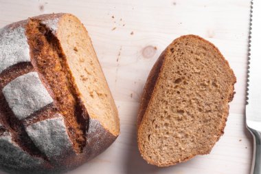 Tahtada dilimlenmiş taze pişmiş kepekli ekmek, geleneksel lezzetli ekmek ve bıçak.