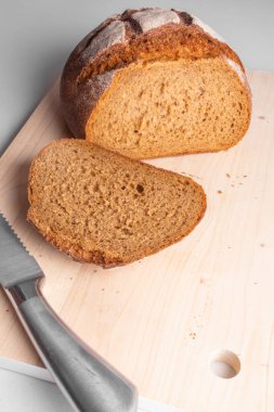 Tahtada dilimlenmiş taze pişmiş kepekli ekmek, geleneksel lezzetli ekmek ve bıçak.