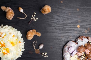 Çikolata söğüt dalları, yumurta, simit, siyah ahşap arka planda narsist çiçekler, mutlu Paskalya tebrik kartları, bahar festivali sezonu. Düz konum, üst görünüm, kopyalama alanı