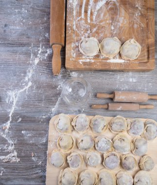 Hamur köftesi pişirmek için ham malzemeler, ahşap tahtada ravioli, hamur köftesi tarifi, un pişirme süreci. Geleneksel Rus pelmeni, et, biber, soğan, un, küf. Üst Manzara. Düz konum
