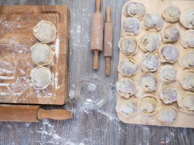 Hamur köftesi pişirmek için ham malzemeler, ahşap tahtada ravioli, hamur köftesi tarifi, un pişirme süreci. Geleneksel Rus pelmeni, et, biber, soğan, un, küf. Üst Manzara. Düz konum