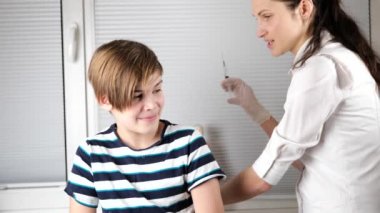 Doktor çocuğa koluna iğne yapıyor.