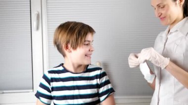 Eldivenli doktor aşı yapmadan önce çocuğun kollarını pamukla dezenfekte ediyor.