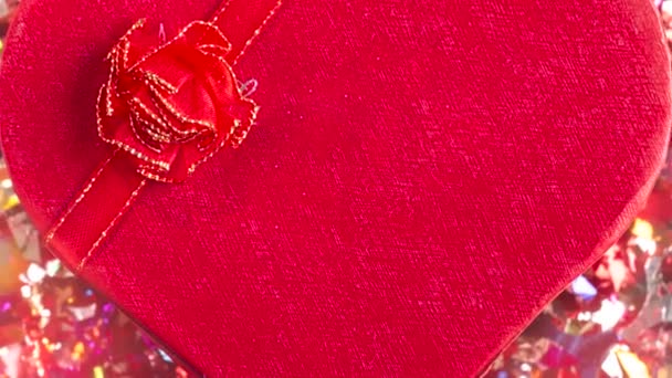 Jelen vagy ajándék doboz szív alakú piros íj és konfetti vörös alapon