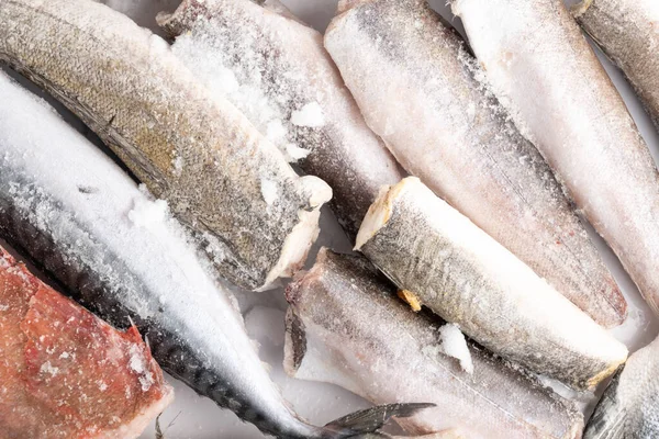 variety of frozen sea sustainable food, fish, shrimps, mackerel, hake, perch, trout, salmon with ice in market, fish store