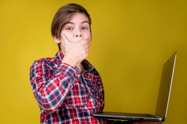 Dizüstü bilgisayarını kullanarak tişörtünü giyen neşeli okul çocuğu evde bilgisayar üzerinde çalışıyor, internetten kendi kendine öğreniyor. Okula geri dön. E-öğrenme, Gamification