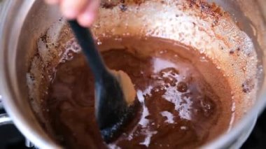 Silikon spatula kasede erimiş çikolatayı karıştırıyor.