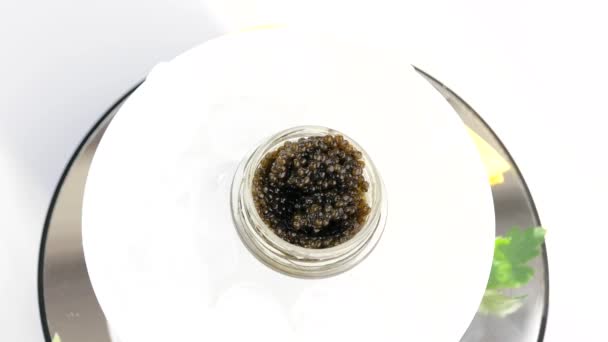 Üvegedény fekete kaviárral jégen citrommal, petrezselyemmel — Stock videók