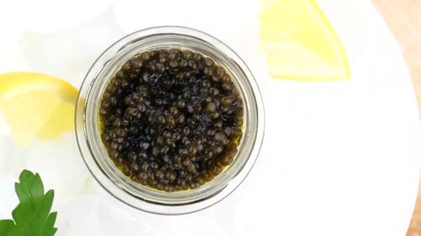 Botol kaca dengan kaviar hitam di atas es dengan lemon, peterseli — Stok Video