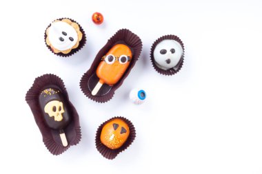 Cadılar Bayramı tatlıları ve ikramlar beyaz arka planda. Hayalet, kafatası ve canavar, parti tatlısı üzerine ürkütücü sembol, göz alıcı şekerler.