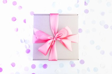 İçinde pembe fiyonk ve şenlikli konfeti olan hediye kutusu. Doğum günü, yabani otlar, Noel tatili ve tebrik konsepti. Düzleştirme biçimi.