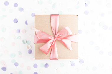 İçinde pembe fiyonk ve şenlikli konfeti olan hediye kutusu. Doğum günü, yabani otlar, Noel tatili ve tebrik konsepti. Düzleştirme biçimi.