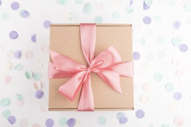 İçinde pembe fiyonk ve şenlikli konfeti olan hediye kutusu. Doğum günü, yabani otlar, Noel tatili ve tebrik konsepti. Düzleştirme biçimi.