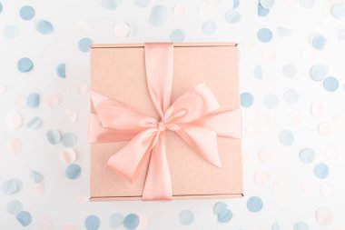 İçinde pembe fiyonk ve şenlikli konfeti olan hediye kutusu. Doğum günü, yabani otlar, Noel tatili ve tebrik konsepti. Düzleştirme biçimi.