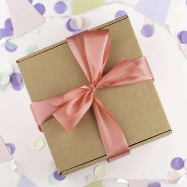 İçinde pembe fiyonk ve şenlikli konfeti olan hediye kutusu. Doğum günü, yabani otlar, Noel tatili ve tebrik konsepti. Düzleştirme biçimi.