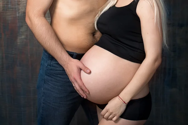 Pregnant woman with husband holding hands on belly — Stock Photo, Image